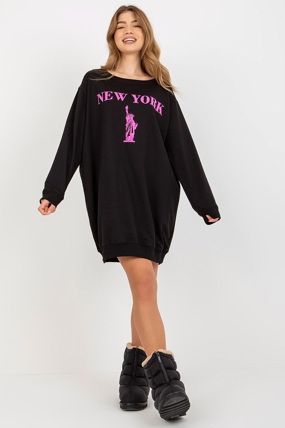 Woman wearing a black sweatshirt dress with 'New York' and a statue of liberty graphic on a white background