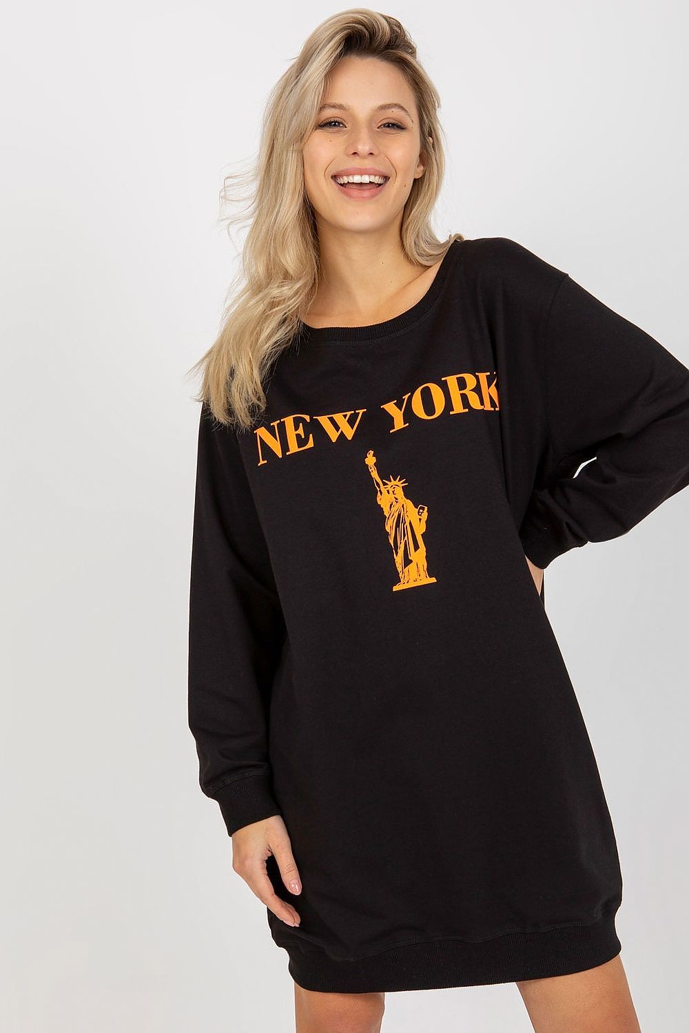 Woman wearing a black sweatshirt dress with 'New York' and Statue of Liberty graphic on a white background