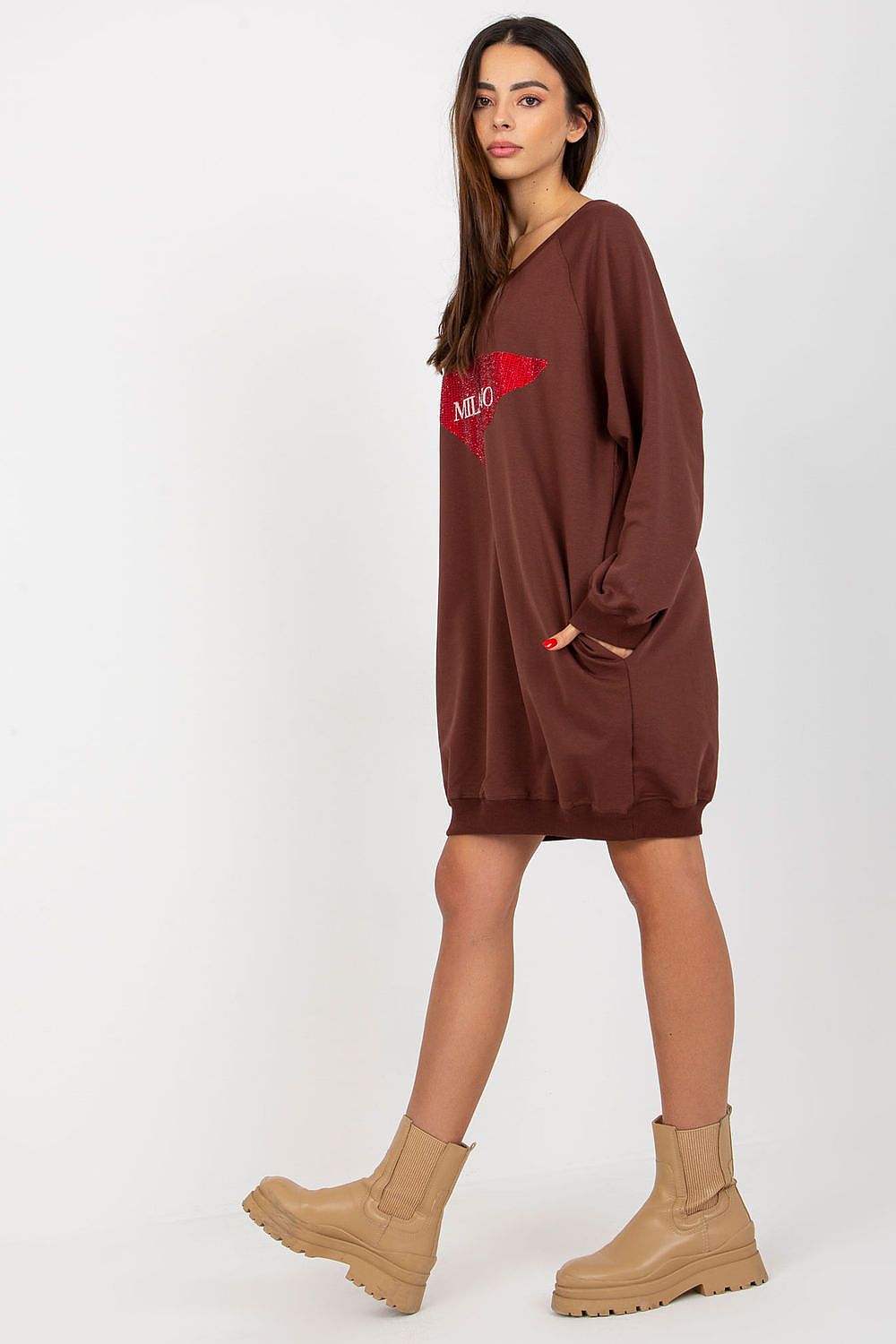 Woman wearing a brown oversized sweater dress with a red logo on a white background