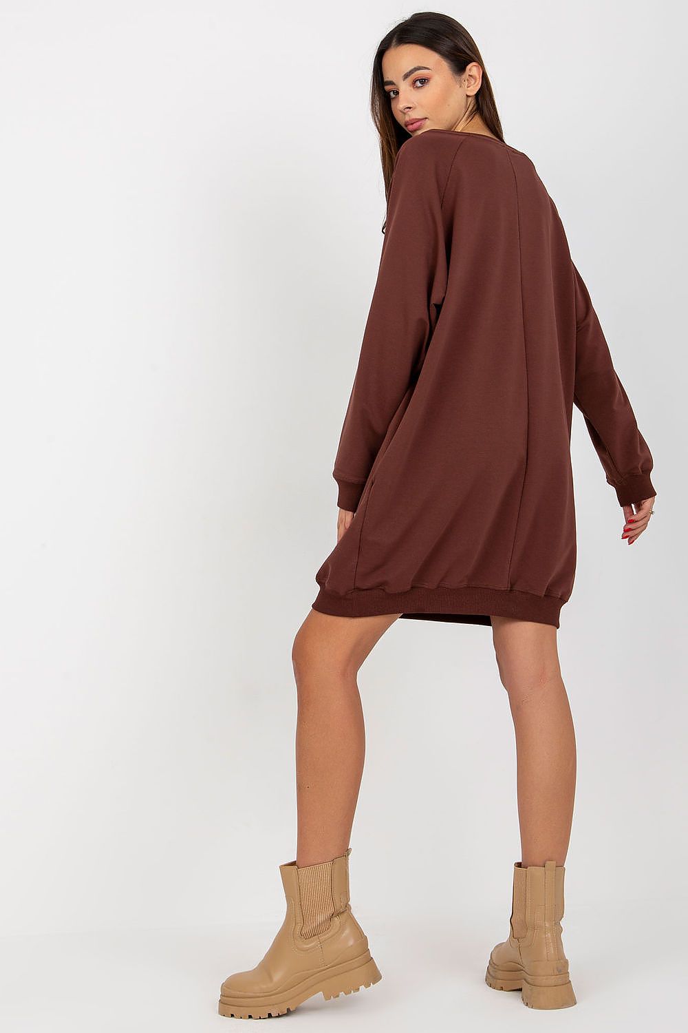 Woman wearing a brown dress with beige boots on a white background