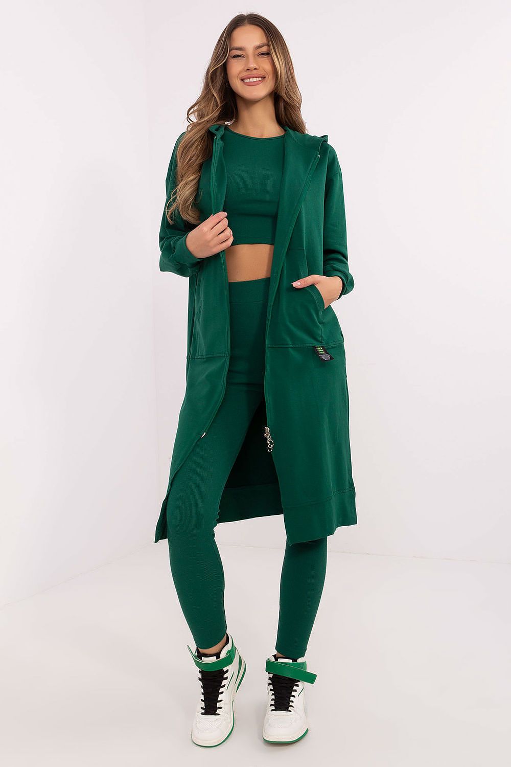 Woman wearing a green outfit with a long coat on a white background