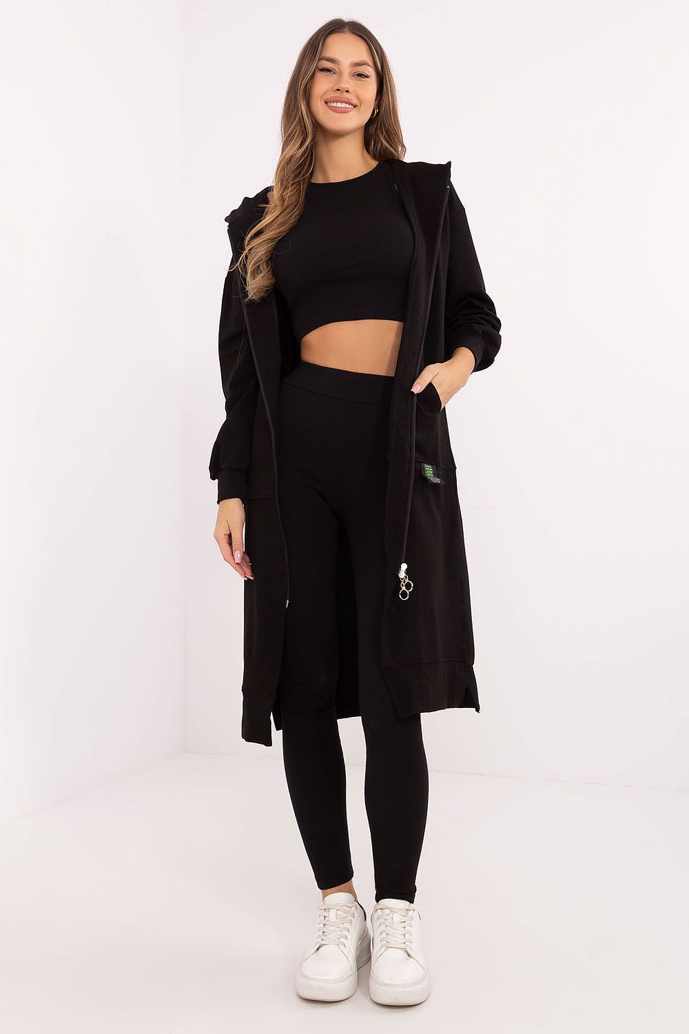 Woman wearing a black outfit with a long coat on a white background