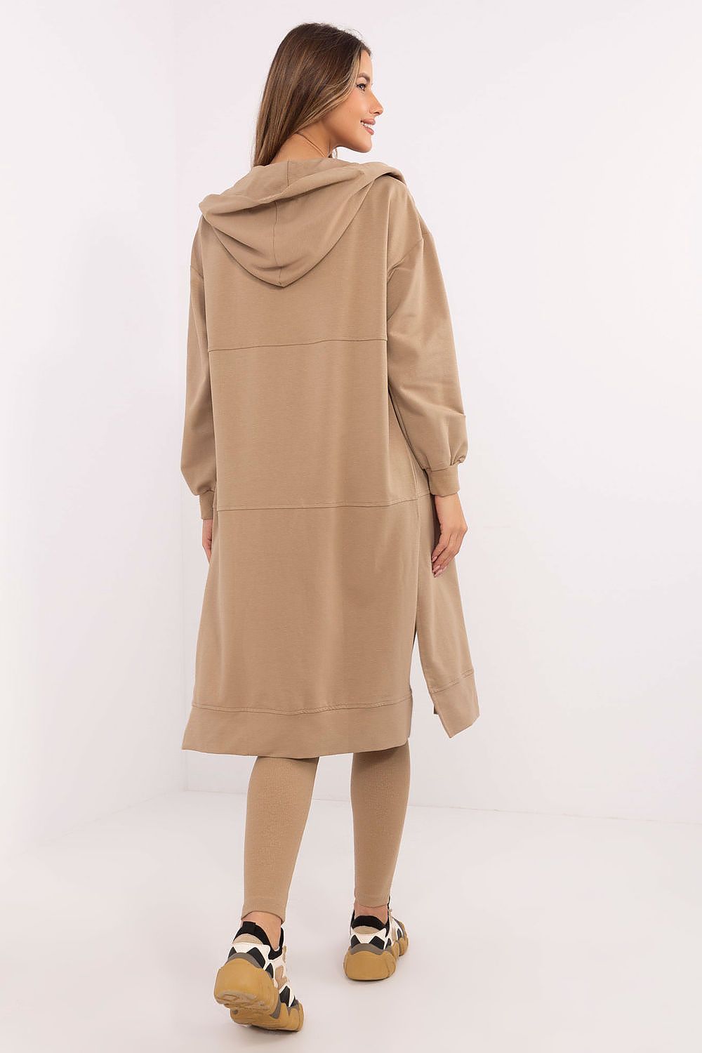 Woman wearing a beige hooded coat and leggings on a white background