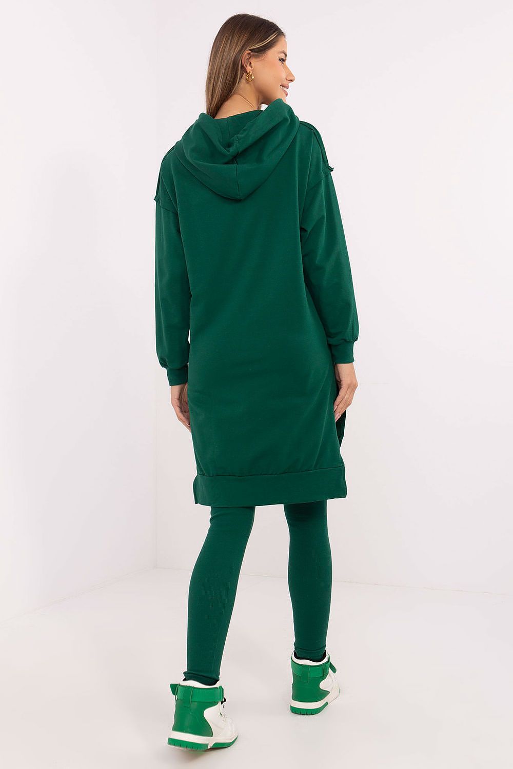 Woman wearing a green hoodie and leggings set on a white background