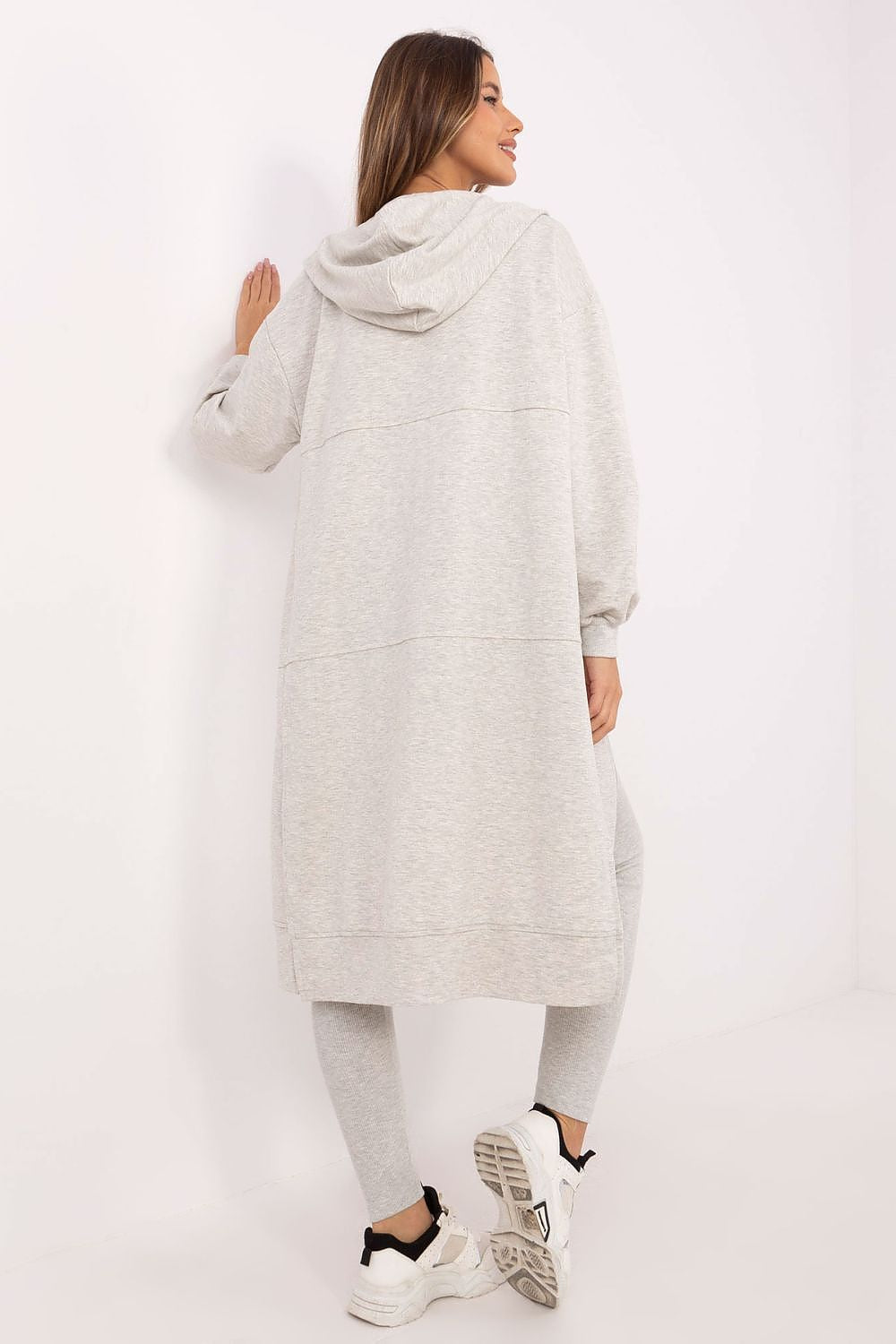 Woman wearing a long light gray hoodie and pants on a white background
