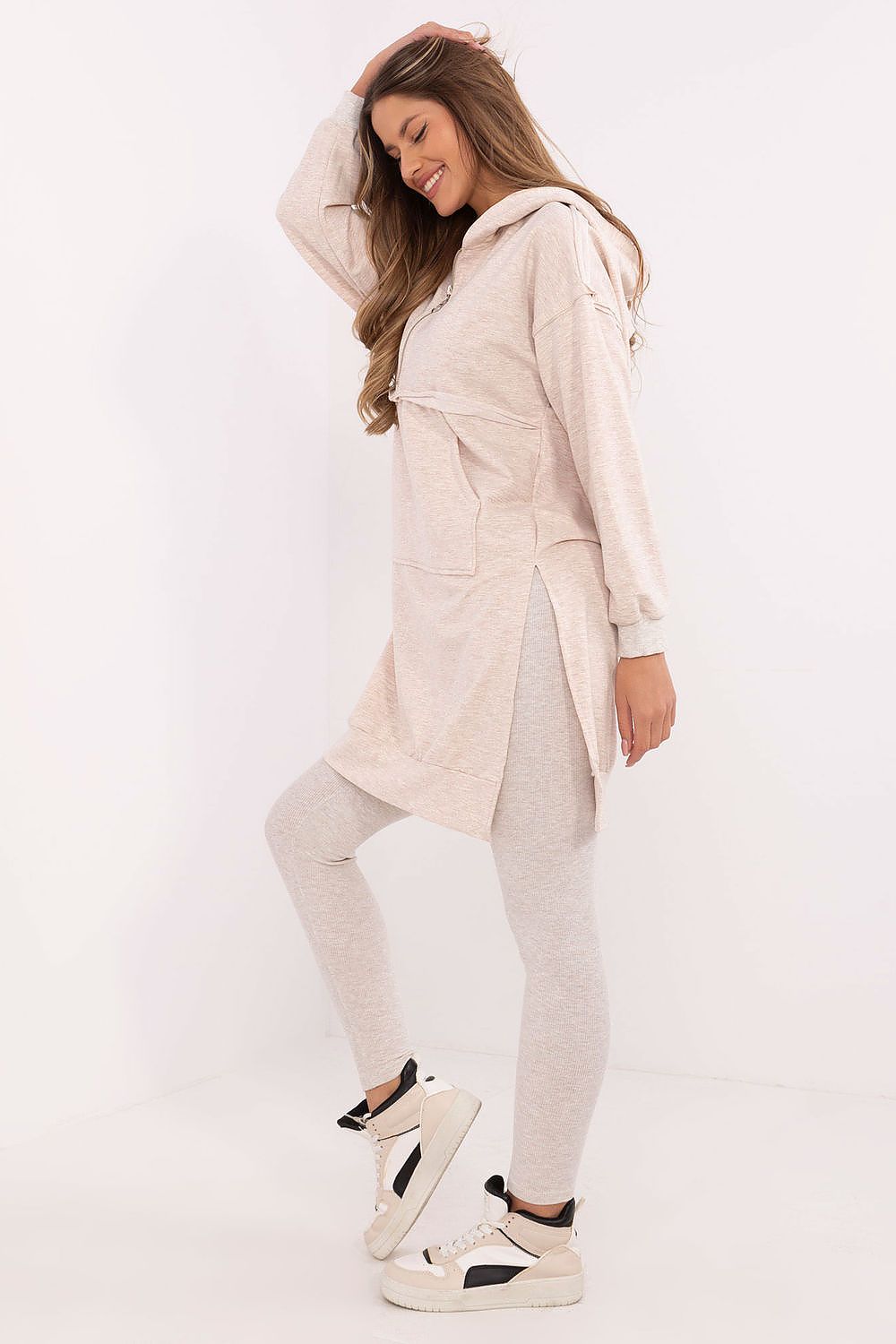 Woman wearing a beige coat, leggings, and sneakers on a white background