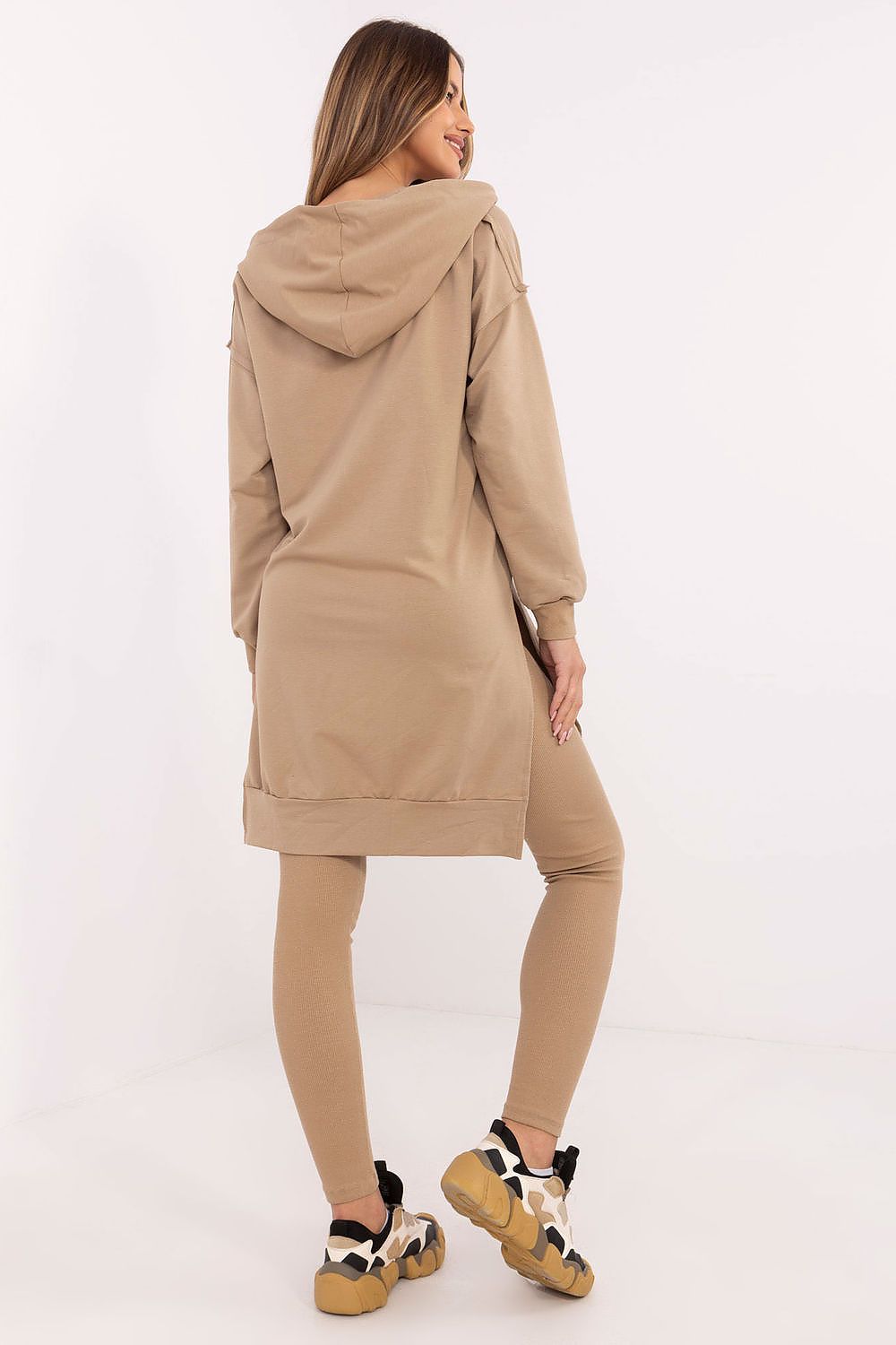  Model in beige hoodie and leggings posing casually.