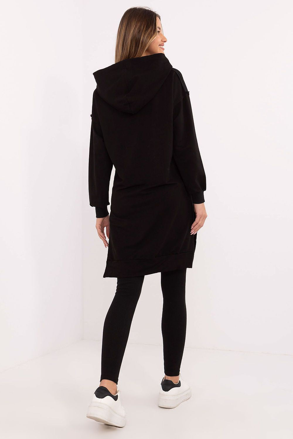 Woman wearing a black hoodie and leggings on a white background