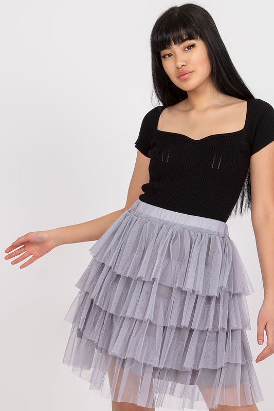 Woman wearing a black top and gray tiered skirt on a white background