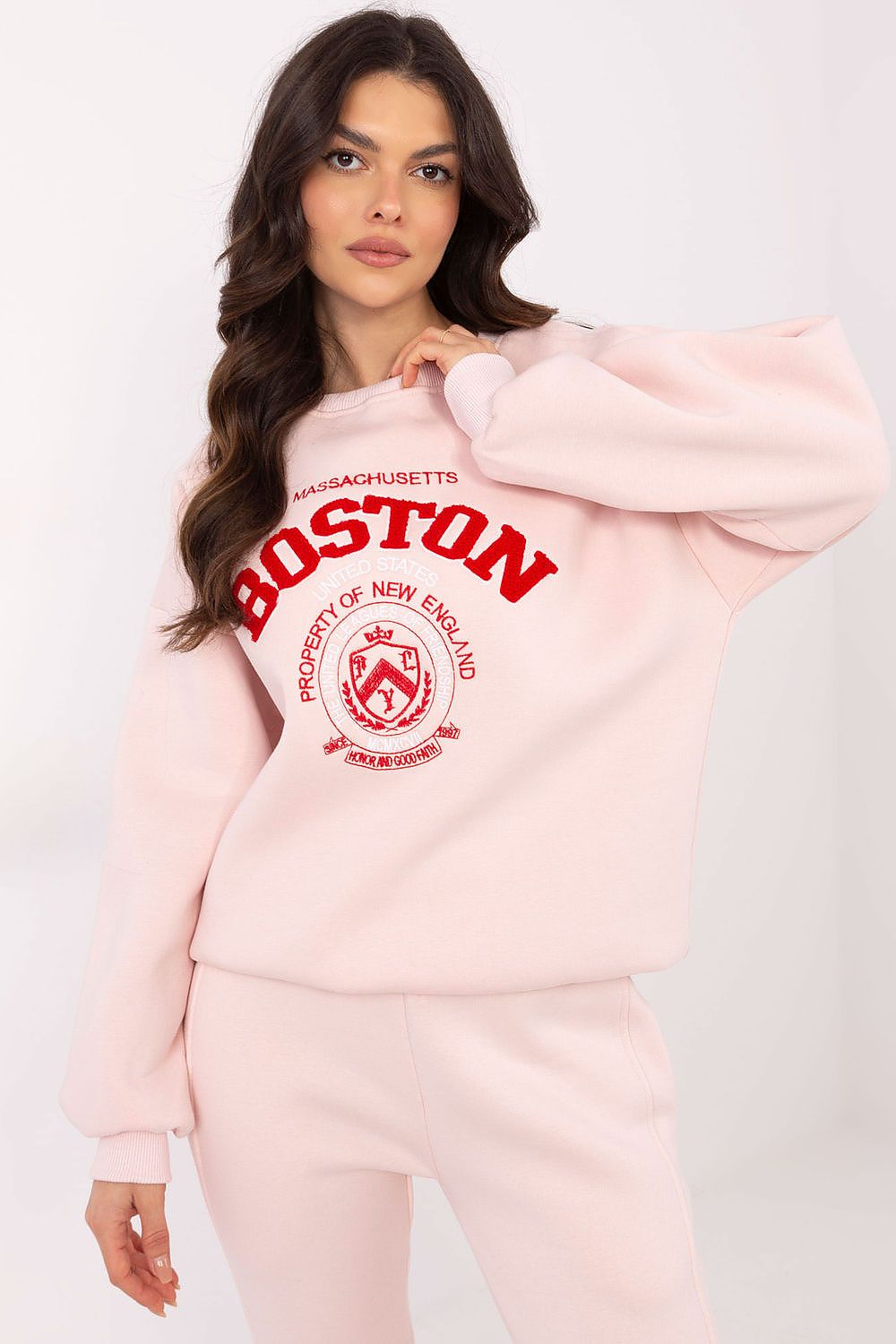 Woman wearing a pink hoodie with 'Boston' text on a white background