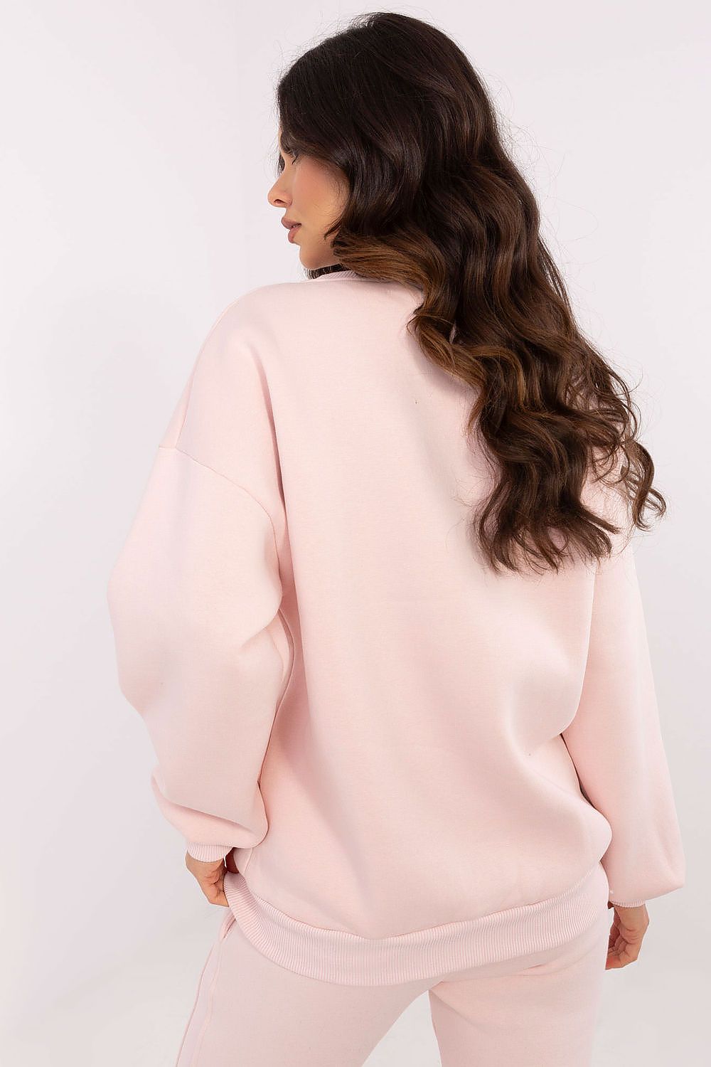 Person wearing a light pink sweatshirt and pants on a white background