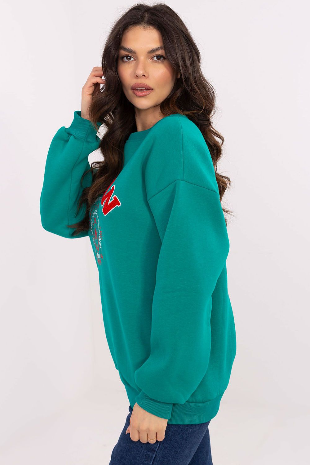 Woman wearing a teal sweatshirt with a logo on a white background