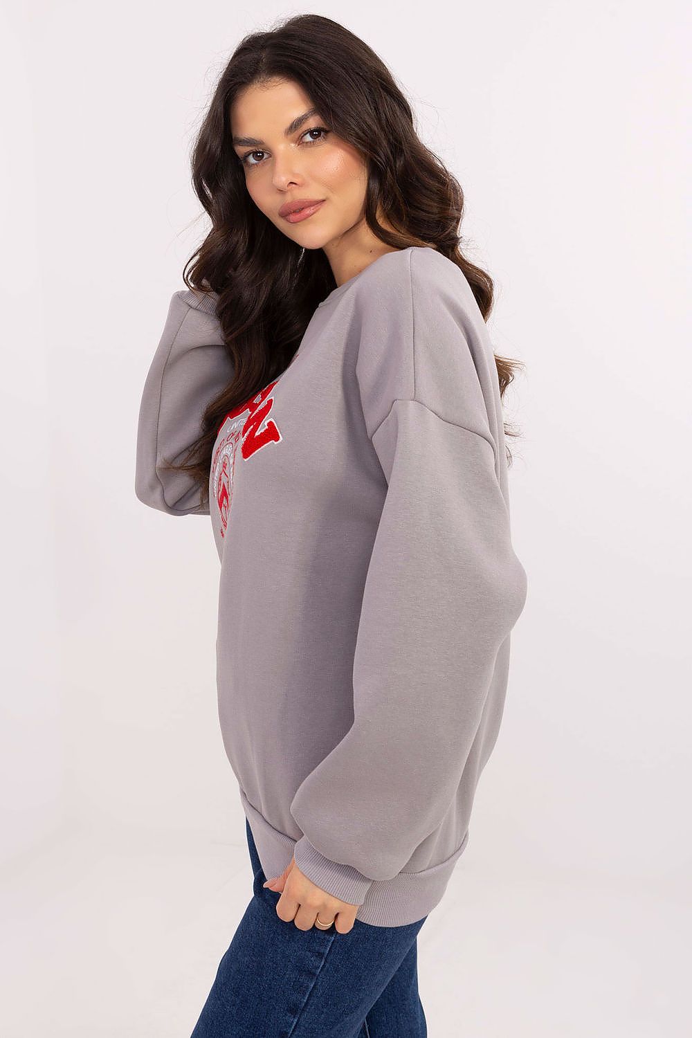 Woman wearing a gray sweatshirt with a red logo on a white background
