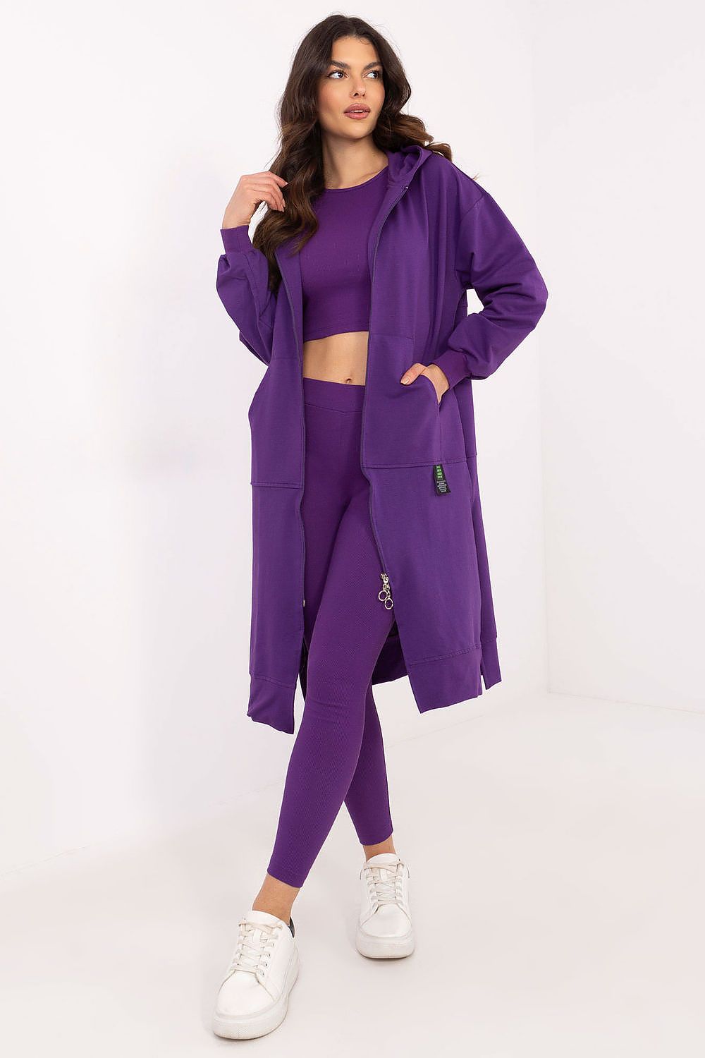 Woman wearing a purple outfit with a long coat on a white background