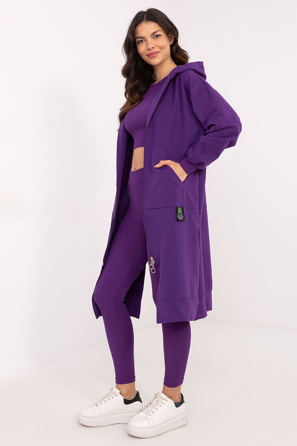 Woman wearing a purple outfit with a long duster on a white background