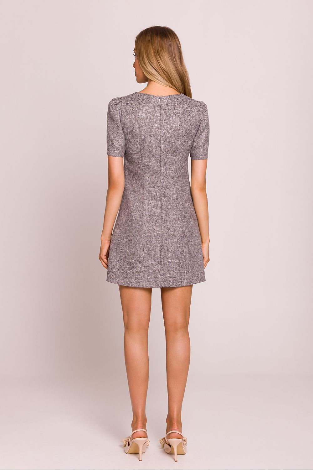 Woman wearing a gray patterned dress against a plain background