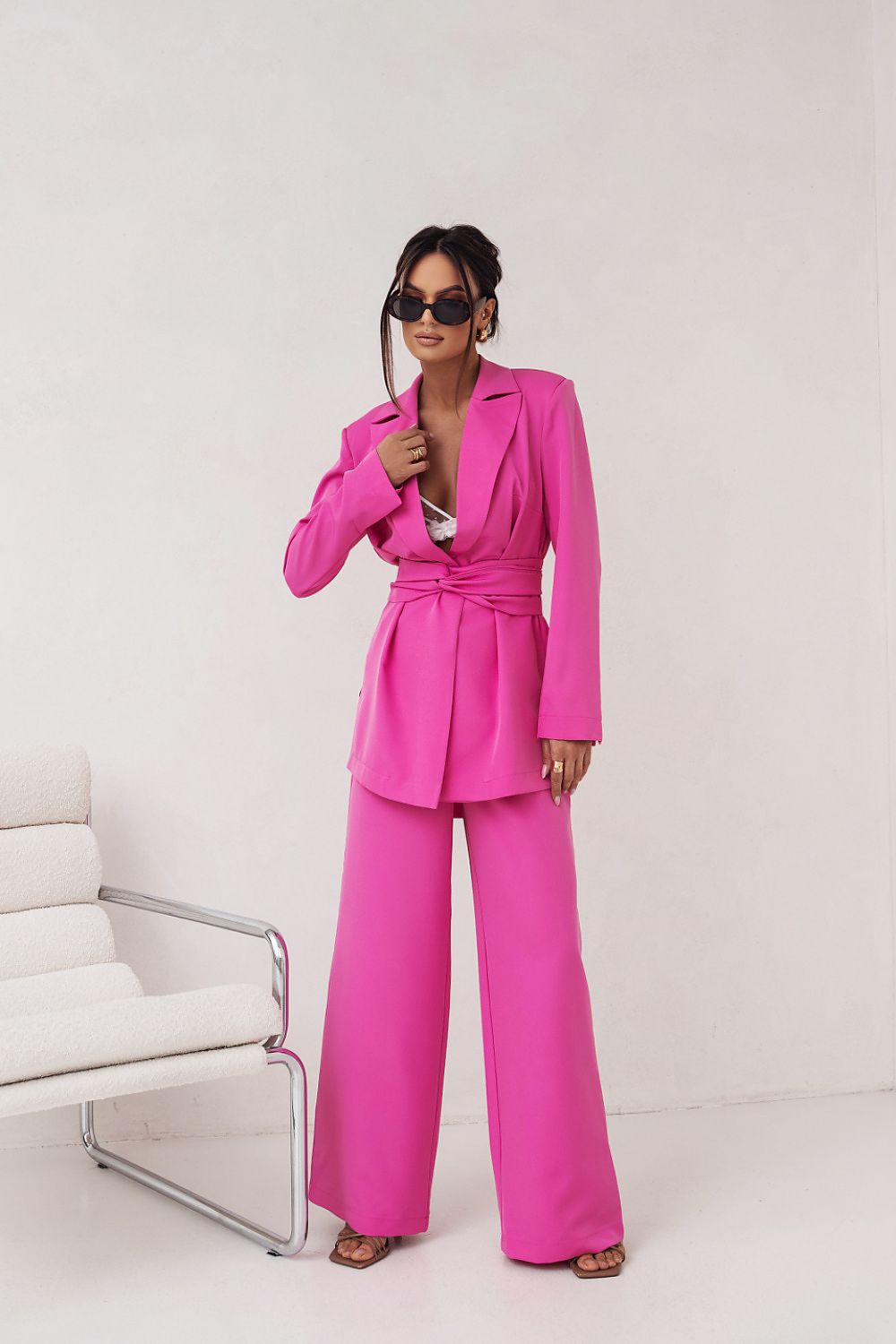 Woman wearing a bright pink suit standing against a white background