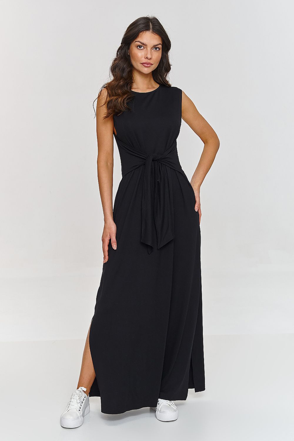 Woman wearing a black sleeveless dress with a tie waist on a white background