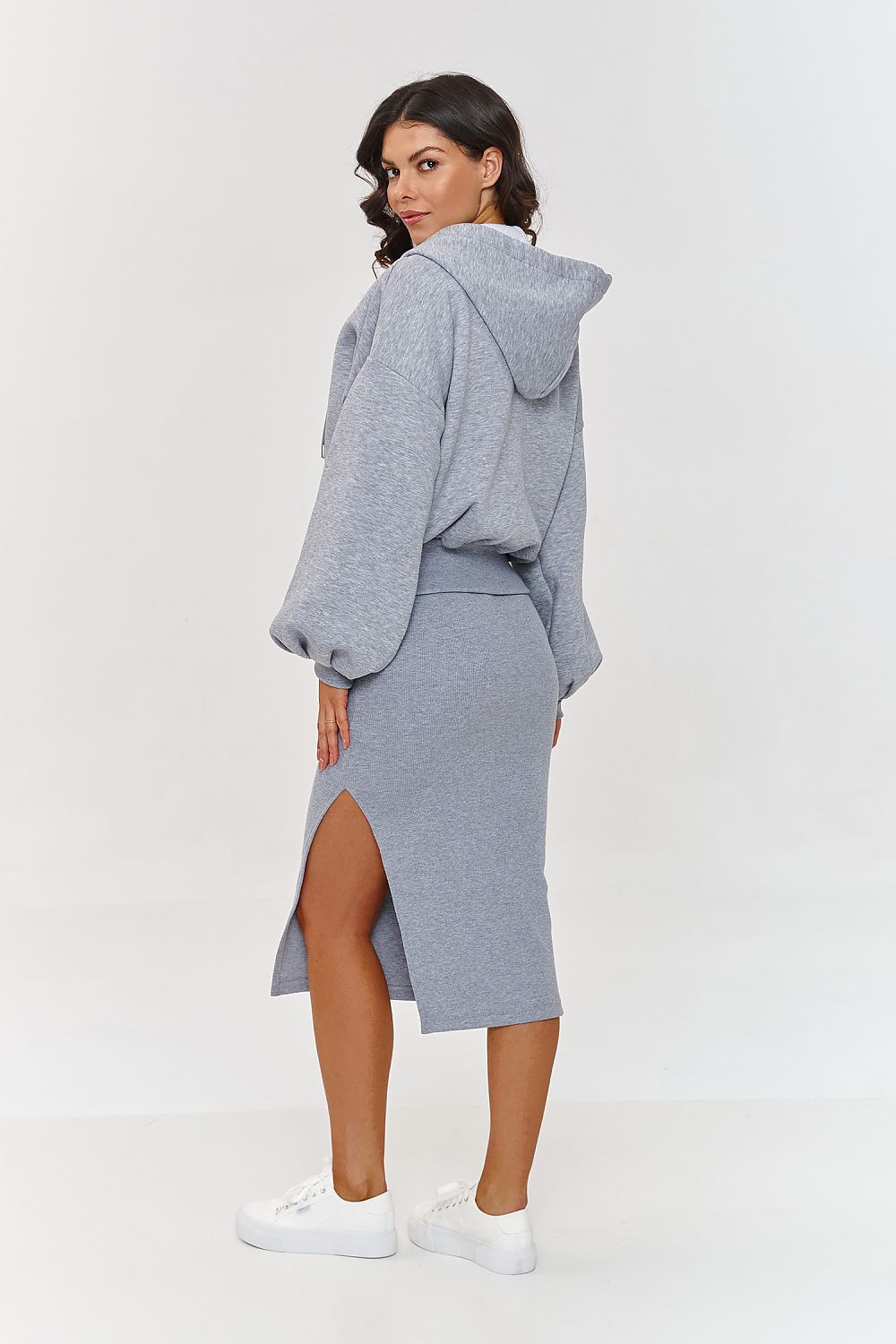 Woman wearing a gray hoodie and skirt set on a white background