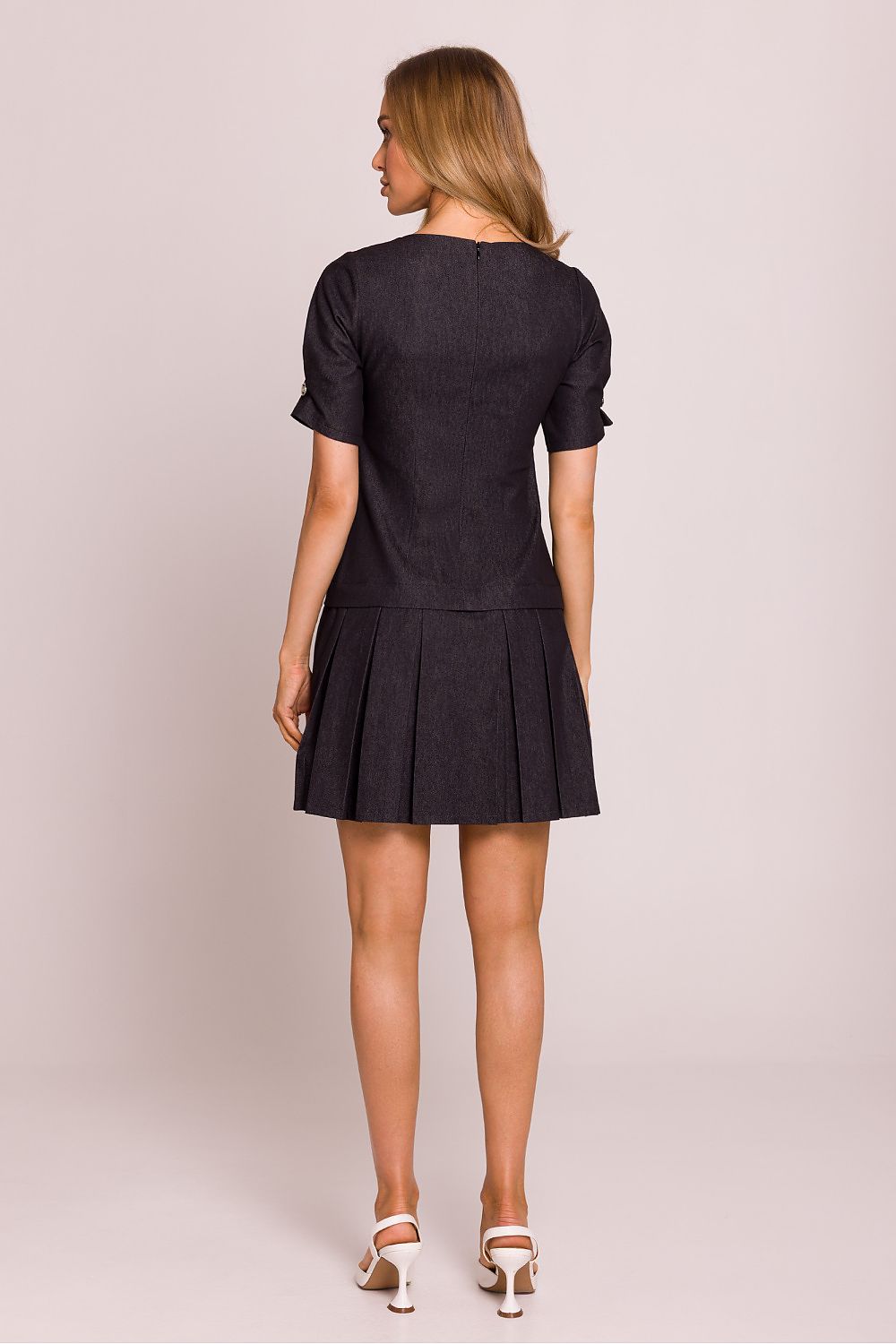 Woman wearing a black dress against a plain background