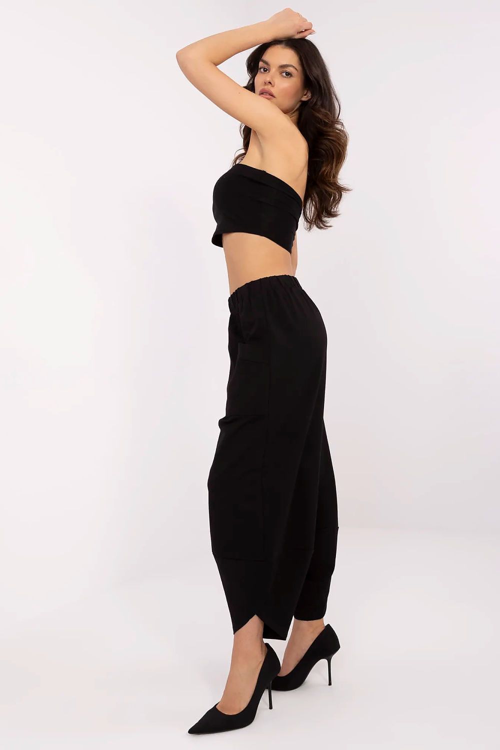 Woman wearing a black strapless top and wide-leg pants on a white background