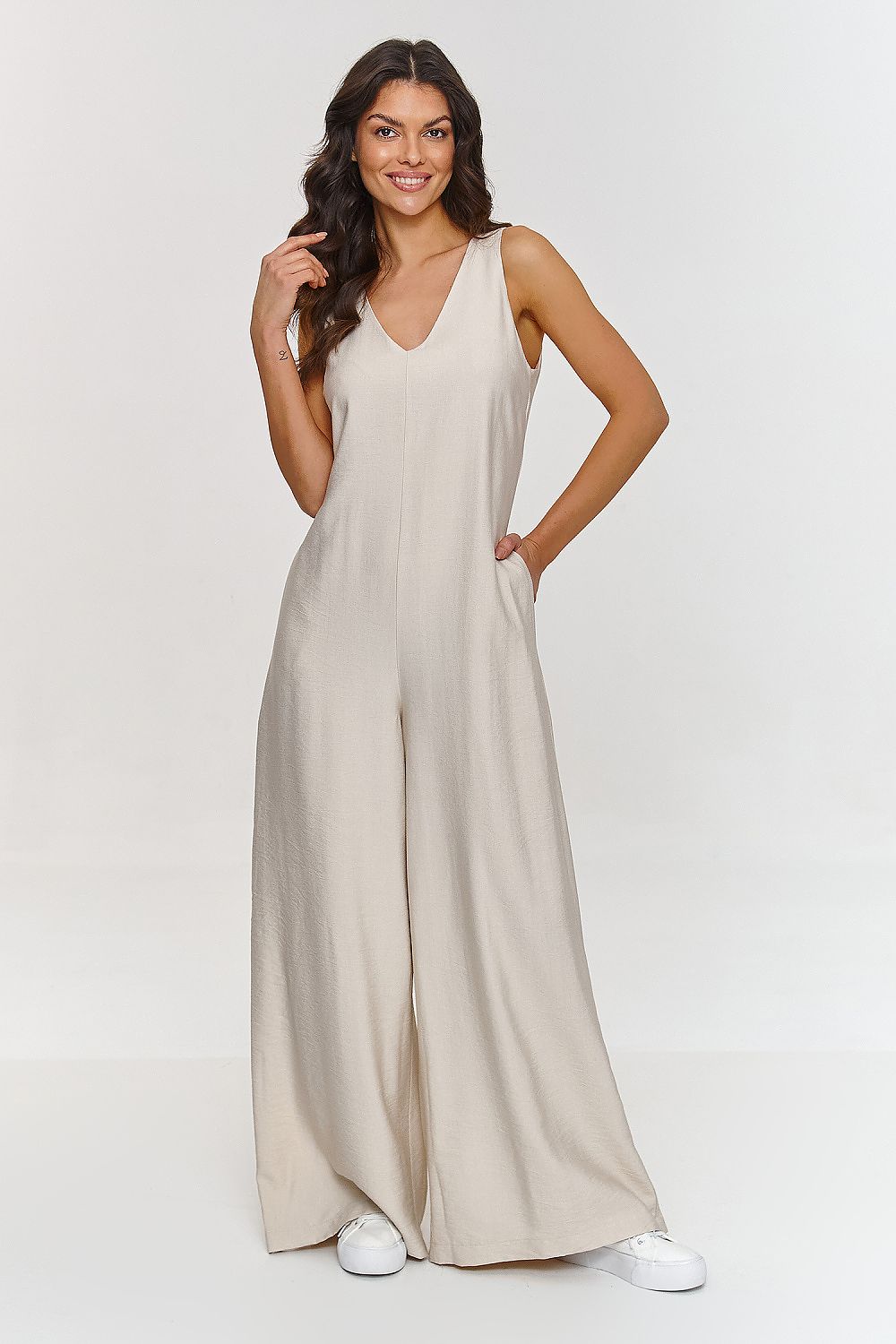 Woman wearing a beige jumpsuit on a white background