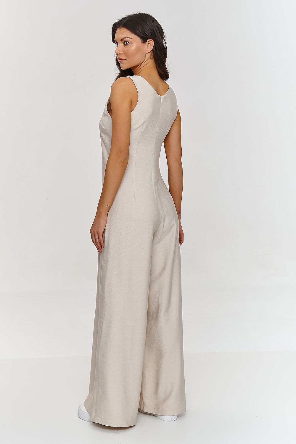 Woman wearing a beige jumpsuit on a white background