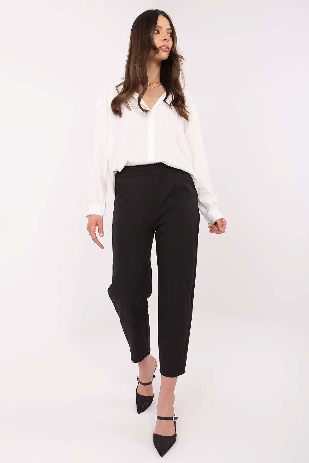 Woman wearing a white blouse and black pants on a white background
