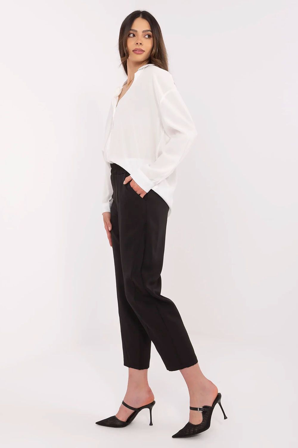 Woman wearing a white blouse and black pants on a white background