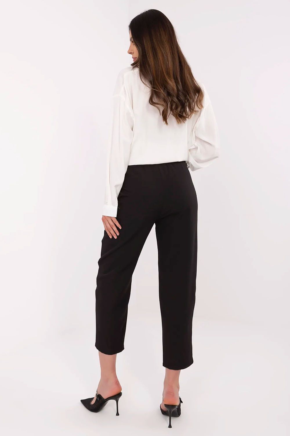 Woman wearing a white blouse and black pants on a white background