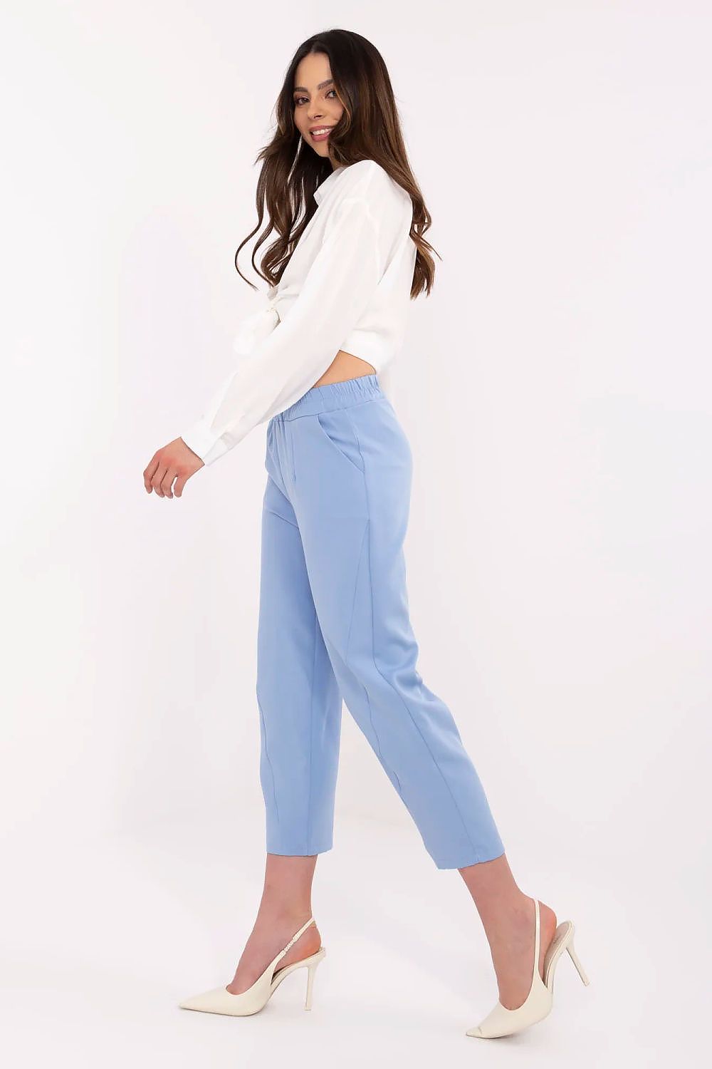 Woman wearing a white sweater and light blue pants on a white background