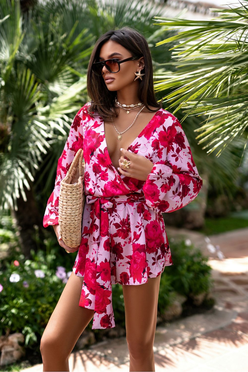 Woman in a pink floral dress standing in a garden setting
