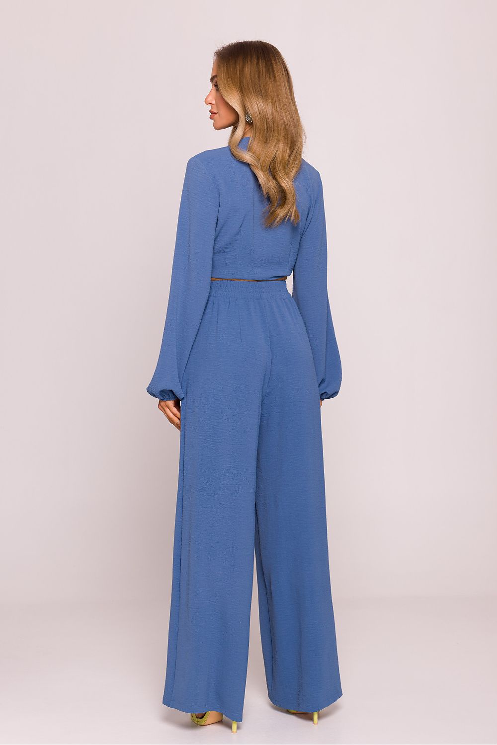 Woman wearing a blue jumpsuit on a light pink background