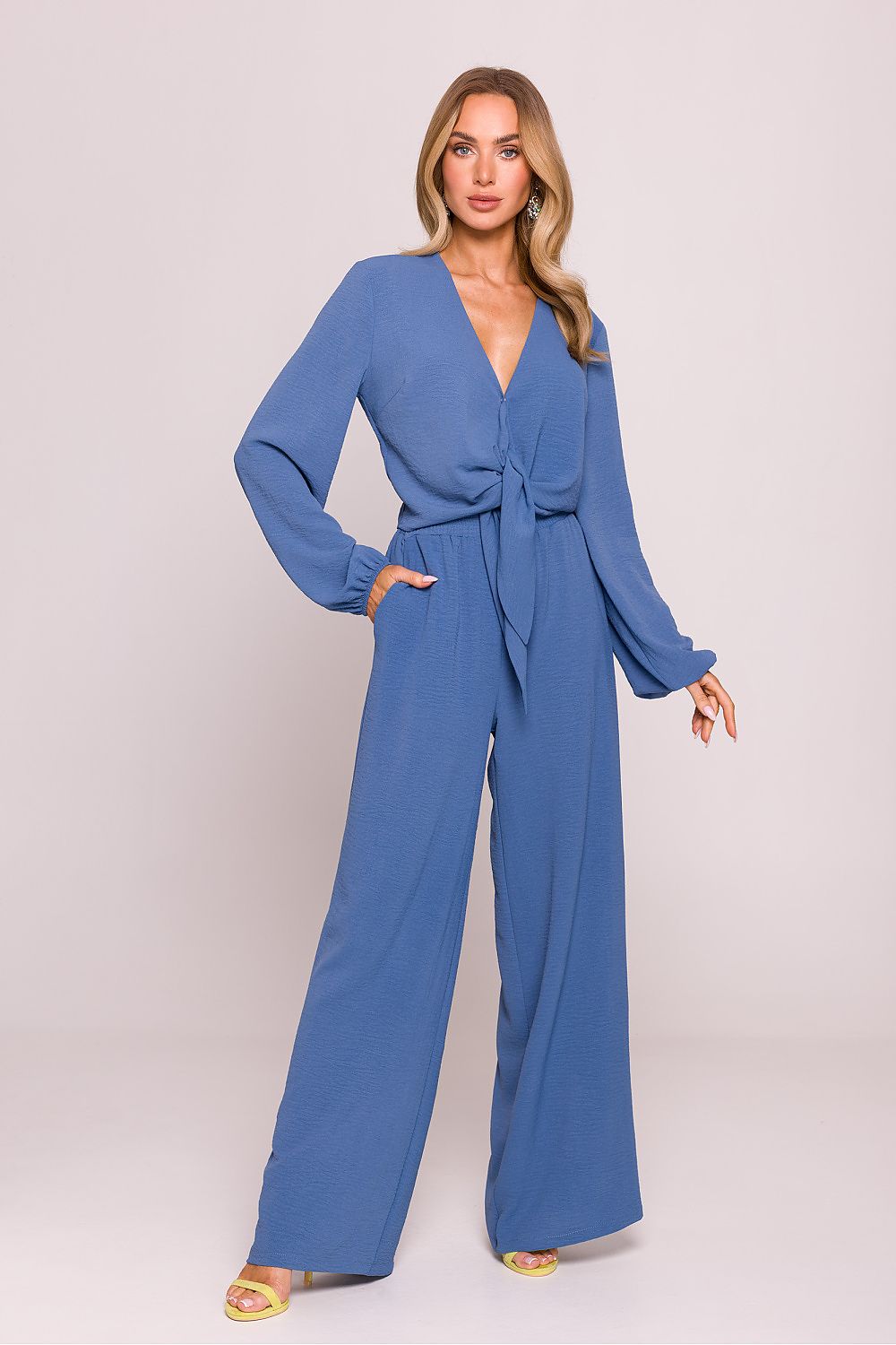 Woman wearing a blue jumpsuit on a plain background