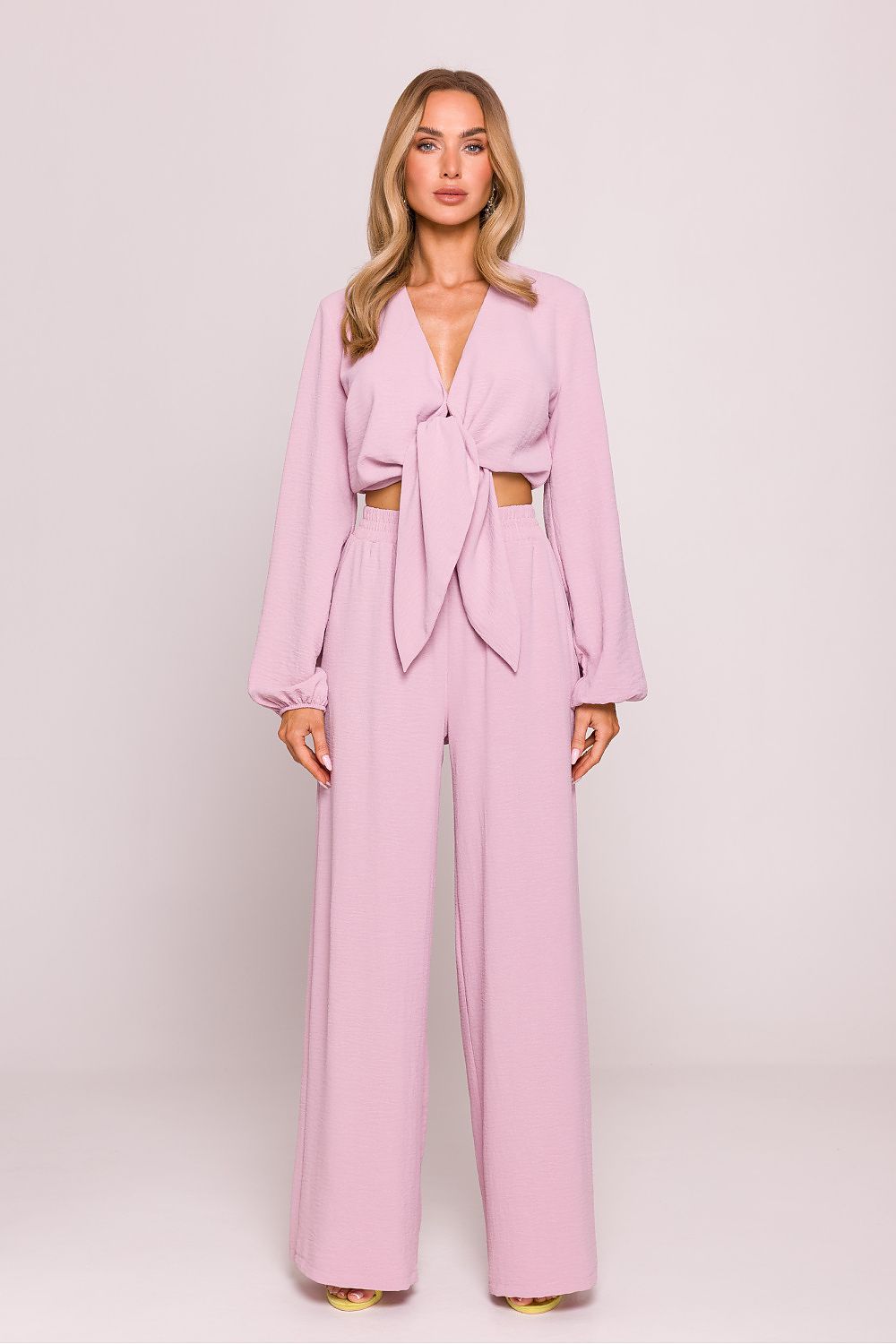 Woman wearing a pink outfit with a matching top and pants on a white background