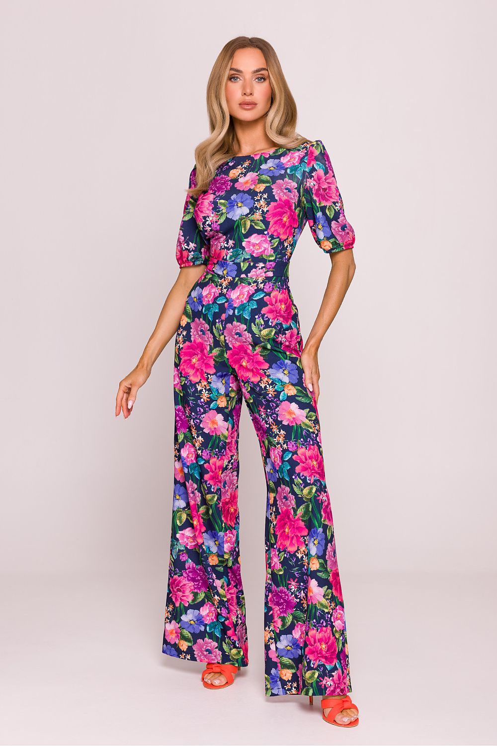 Woman wearing a floral jumpsuit on a plain background