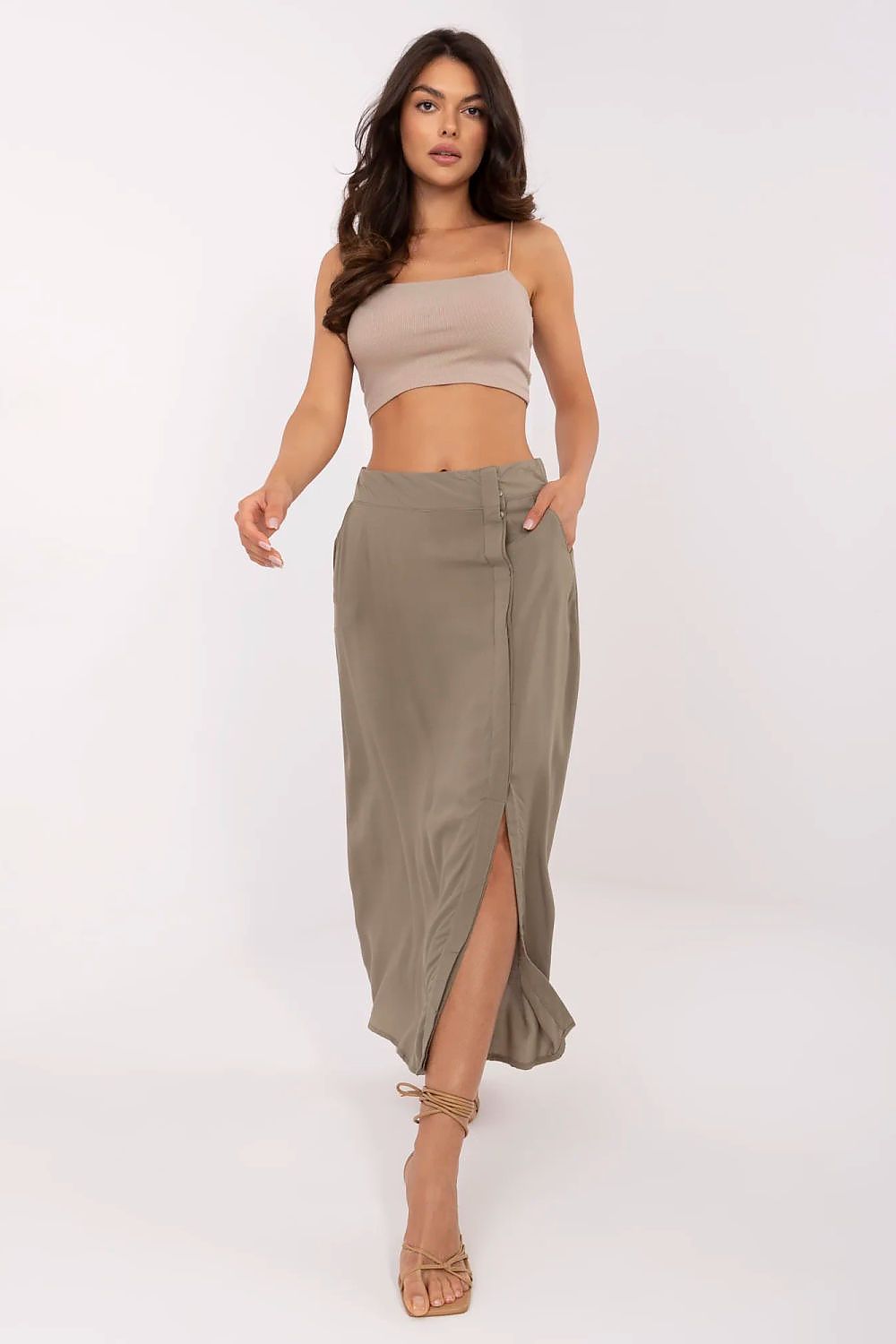 Woman wearing a beige top and olive green skirt on a white background
