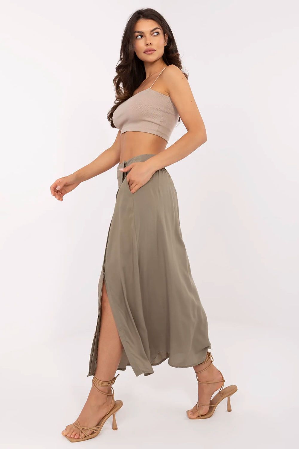 Woman wearing a beige top and olive green skirt on a white background