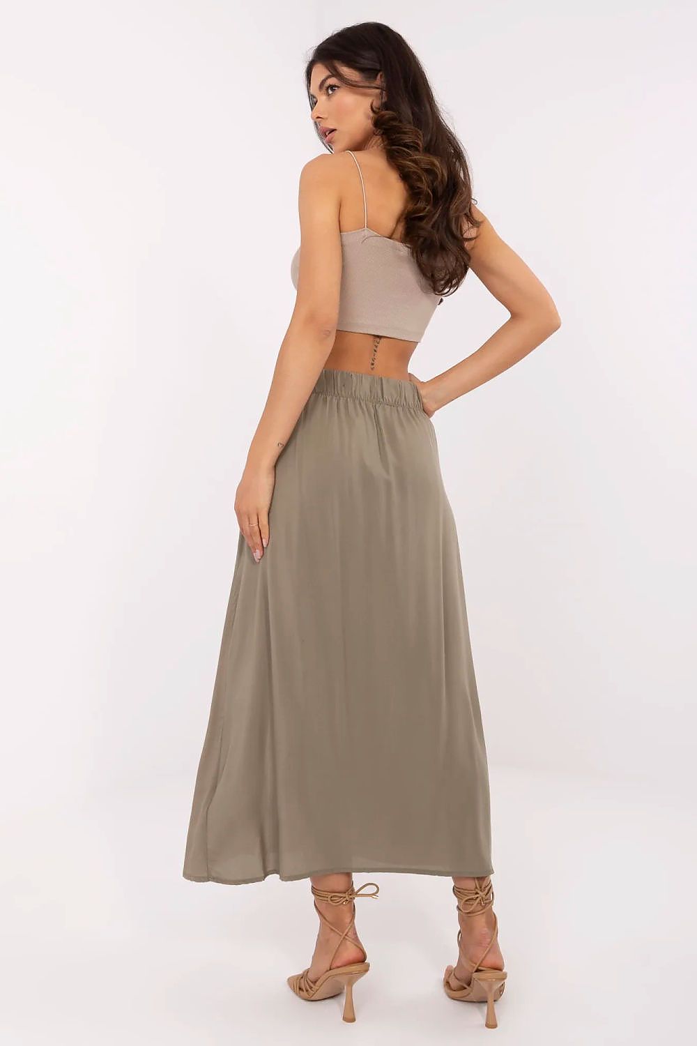 Woman wearing a beige strapless top and long olive green skirt on a white background