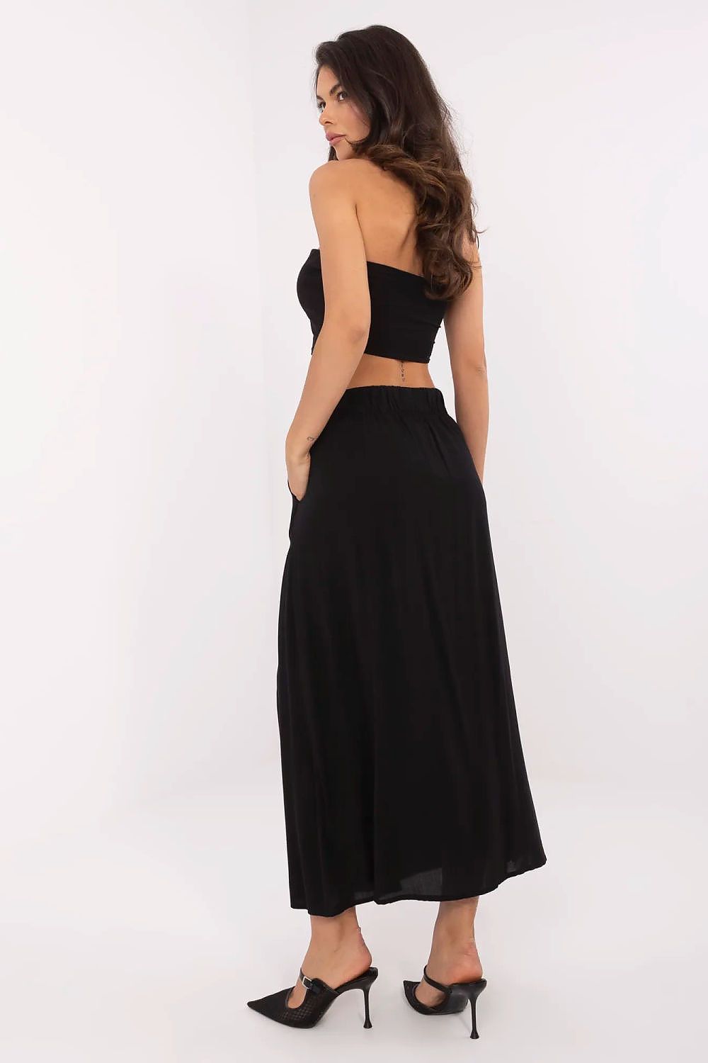 Woman wearing a black strapless top and long black skirt on a white background