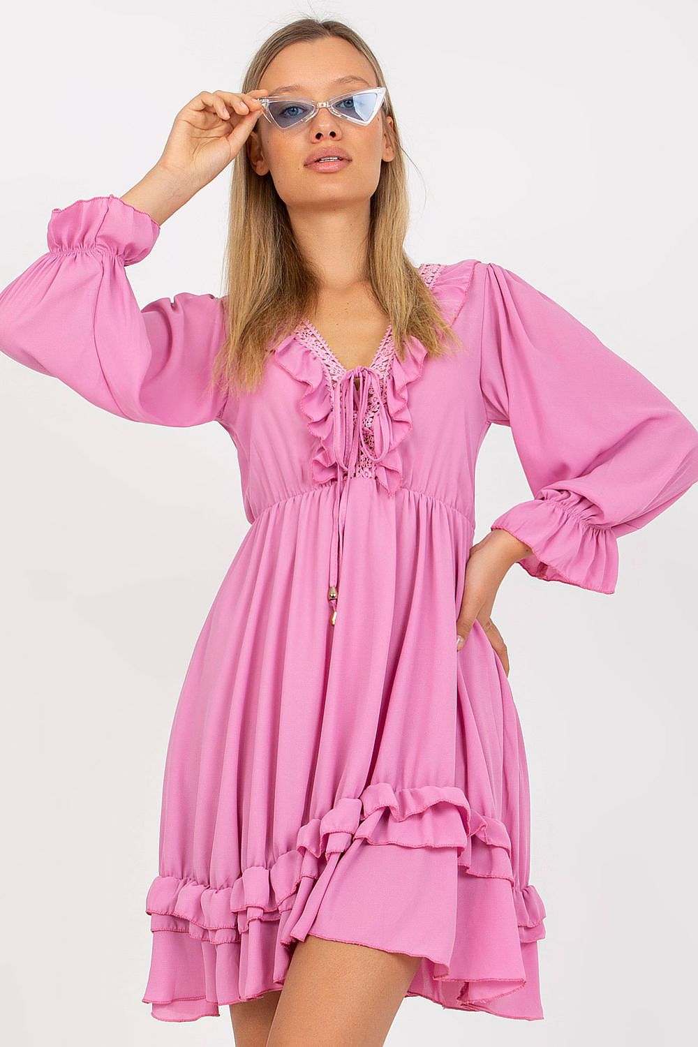 Woman wearing a pink dress with long sleeves on a white background