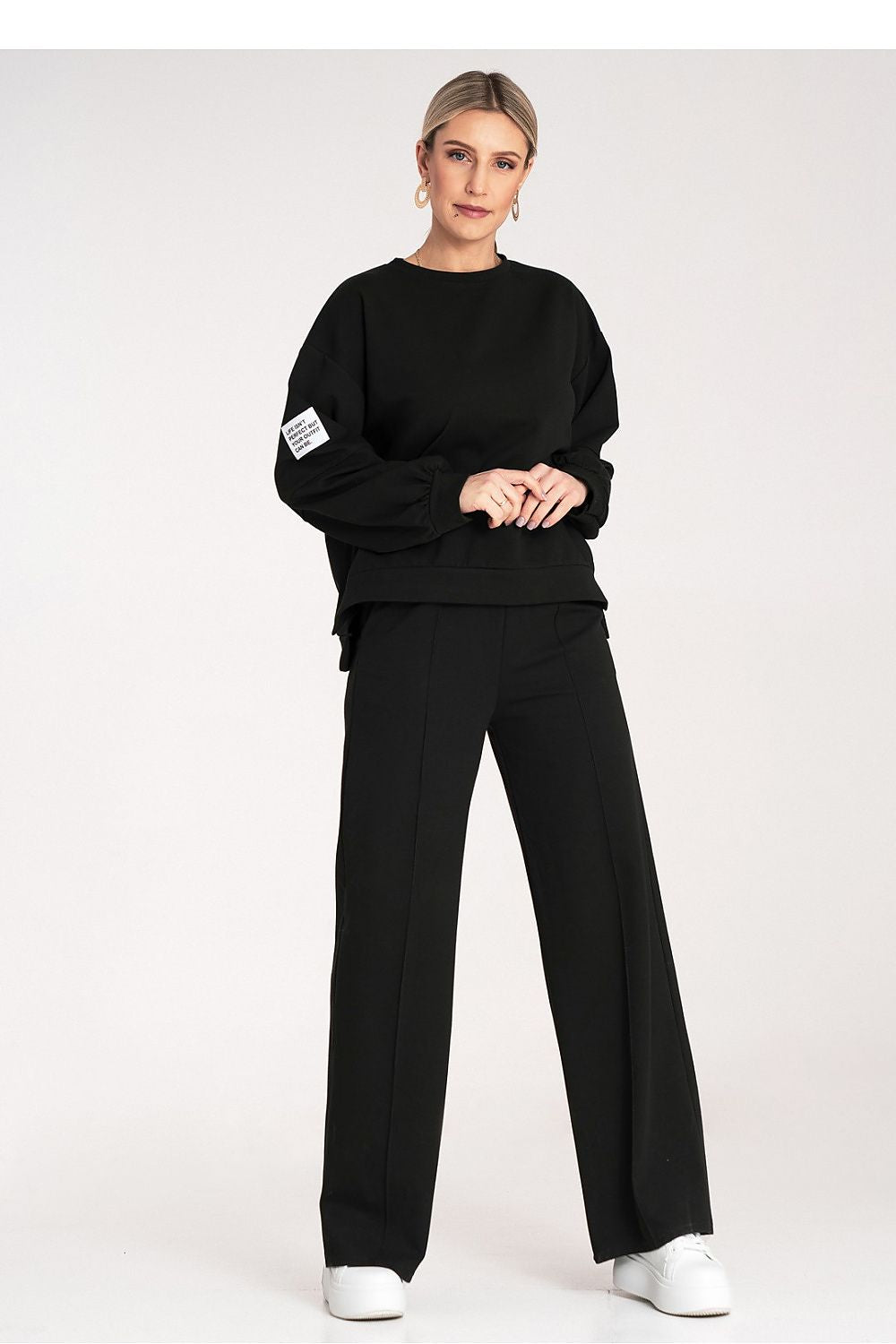 Person wearing a black outfit with white sneakers on a white background
