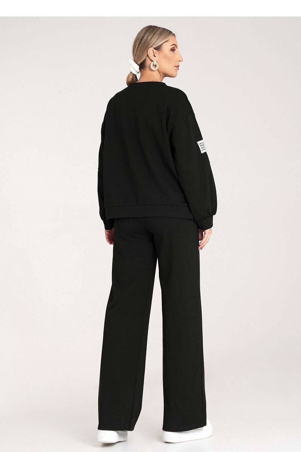 Person wearing a black outfit with a logo on a white background