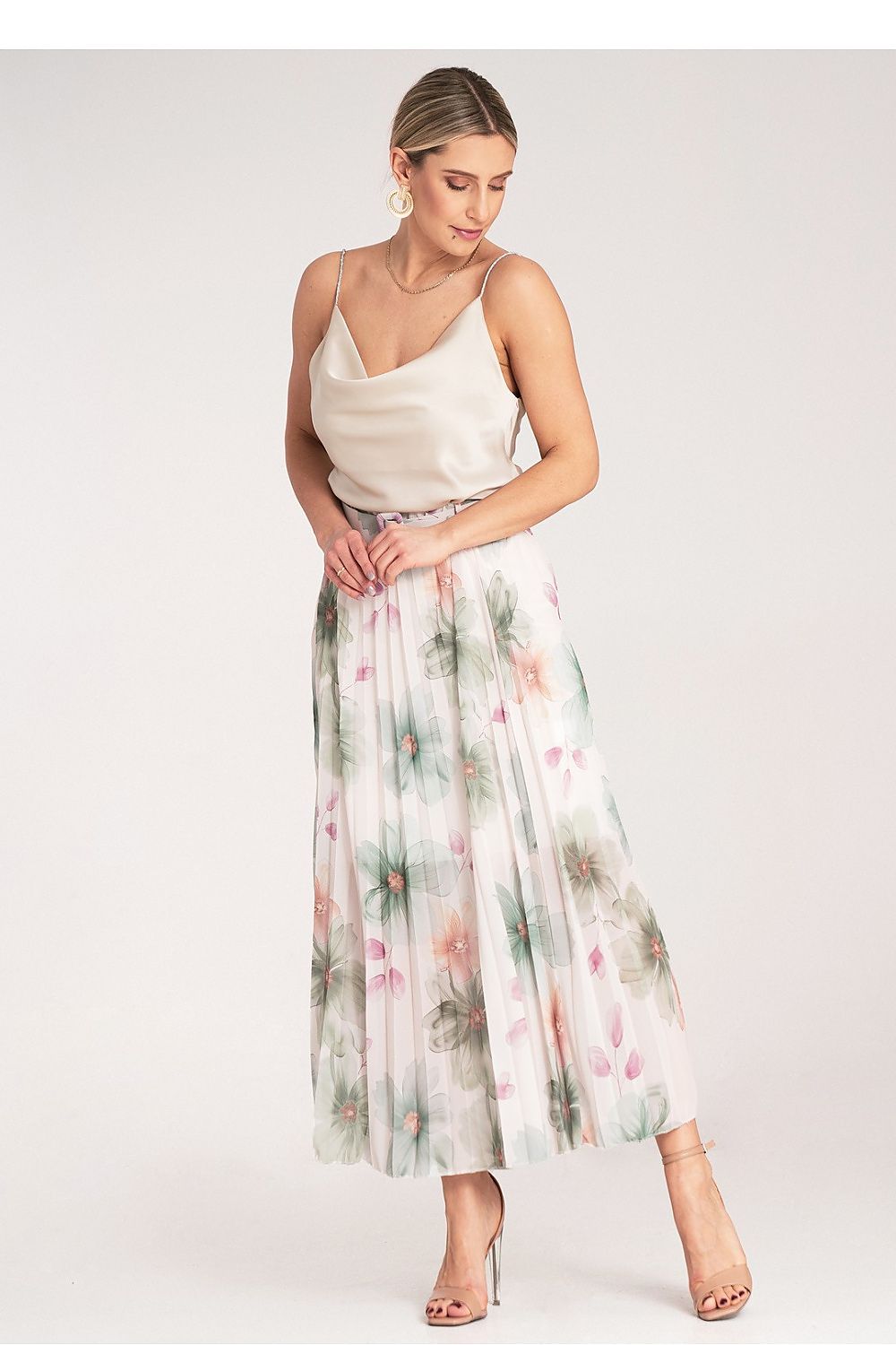 Woman wearing a floral skirt and white top on a plain background