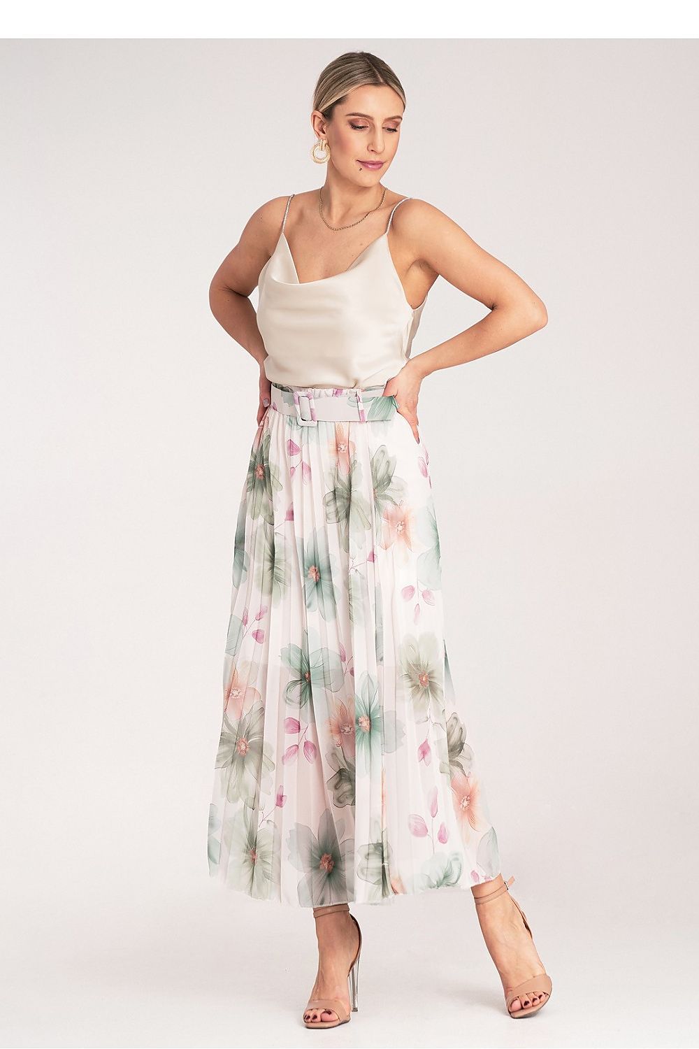 Woman wearing a floral skirt and white top on a plain background