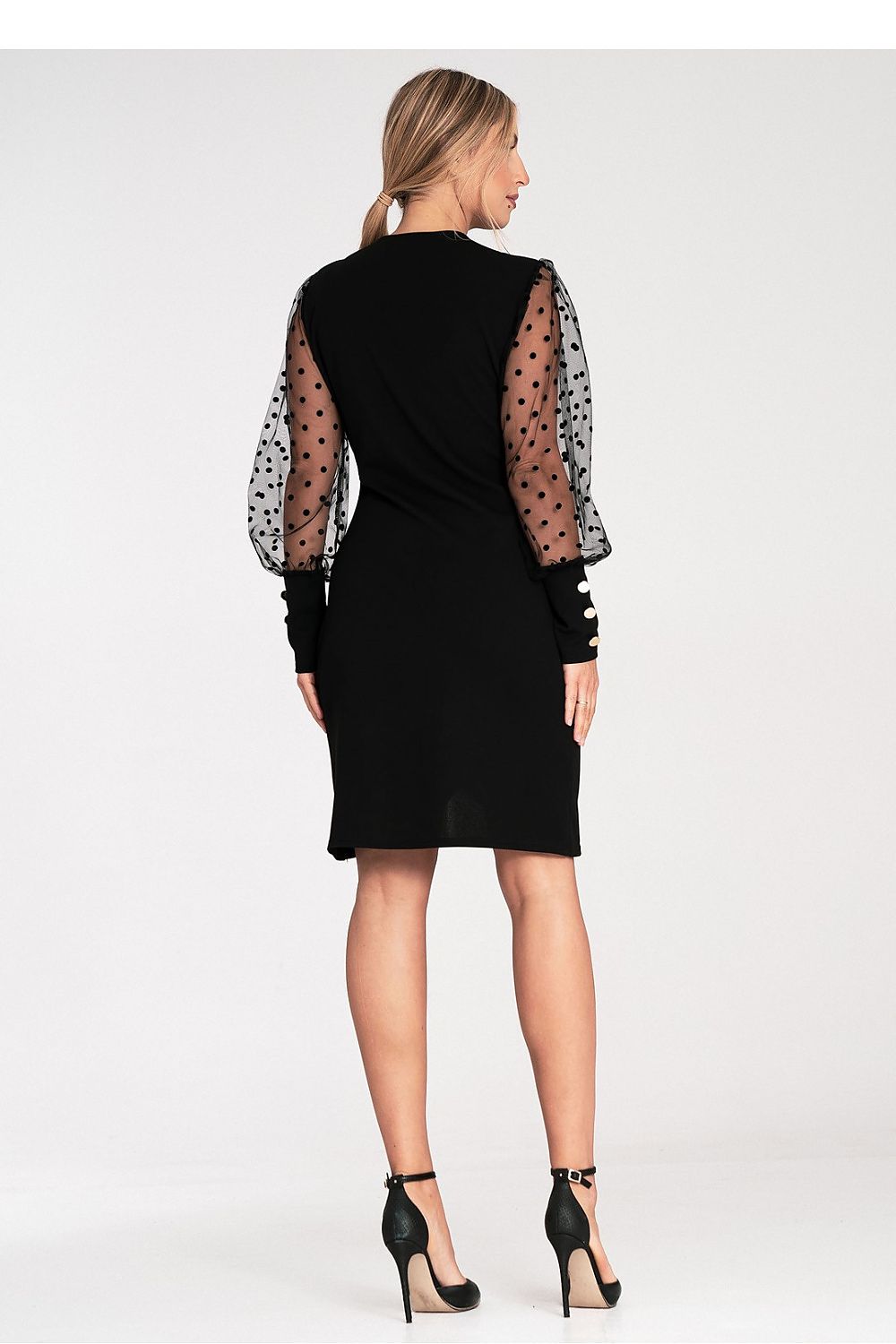 Woman wearing a black dress with sheer sleeves on a white background