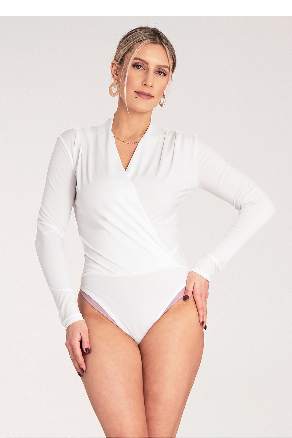 Woman wearing a white long-sleeve swimsuit against a plain background