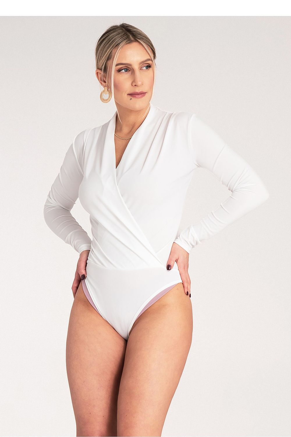 Woman wearing a white bodysuit against a plain background
