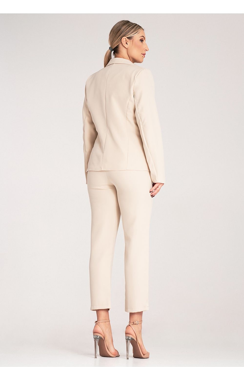 Woman wearing a beige suit on a plain background