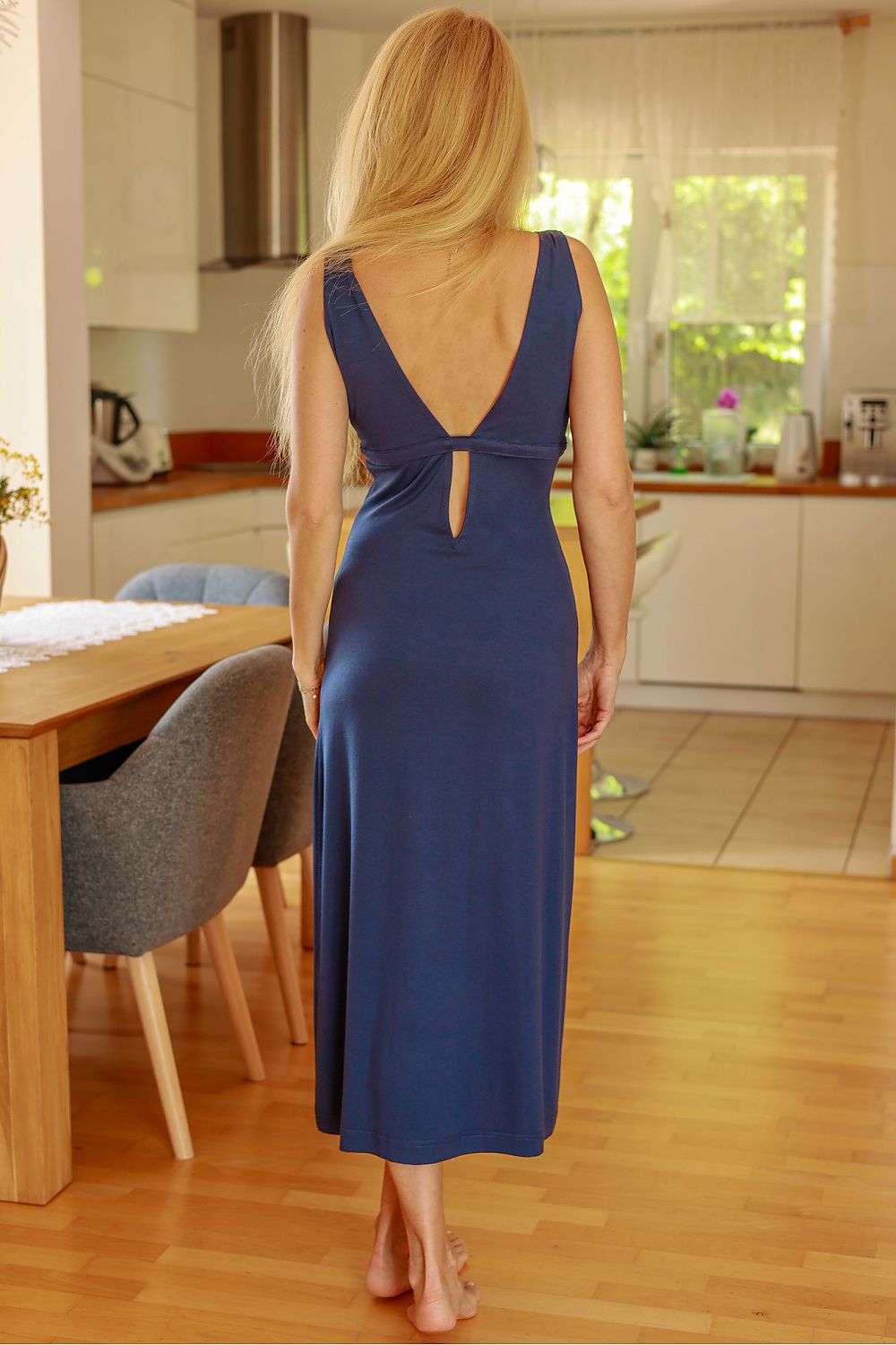 Woman in a blue dress standing in a kitchen